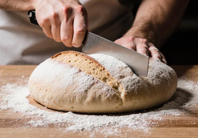 Dough being scored by a baker with a blade